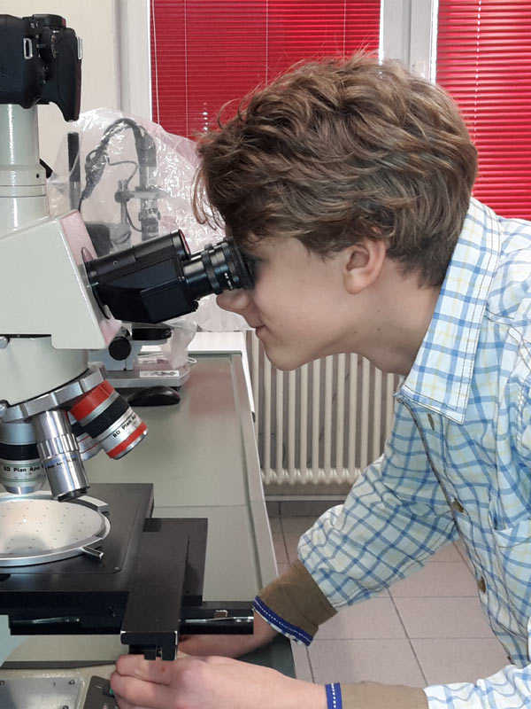 Ein Kind sieht durch ein Mikroskop in unserm außerschulischen Forschungszentrum
