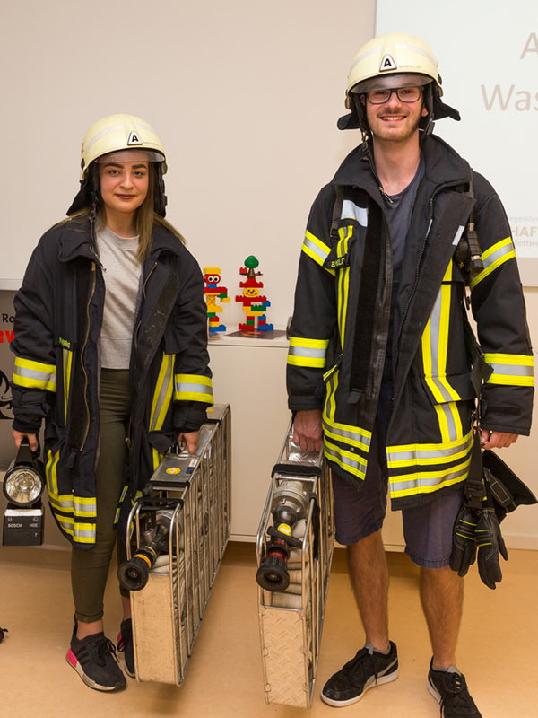 Zwei Teilnehmer eines Ausflugs des Campus Schule-Wirtschaft in Feuerwehruniform